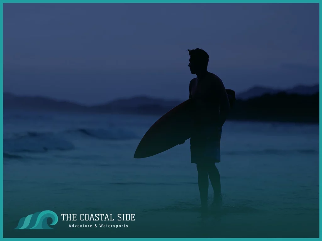 Man getting ready to surf at night in the ocean