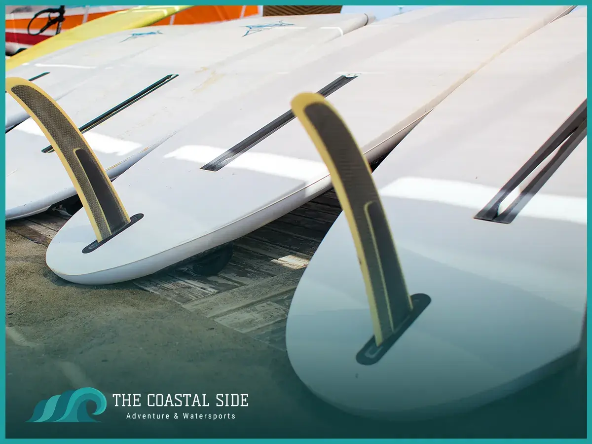 A row of white paddle boards lined up upside down