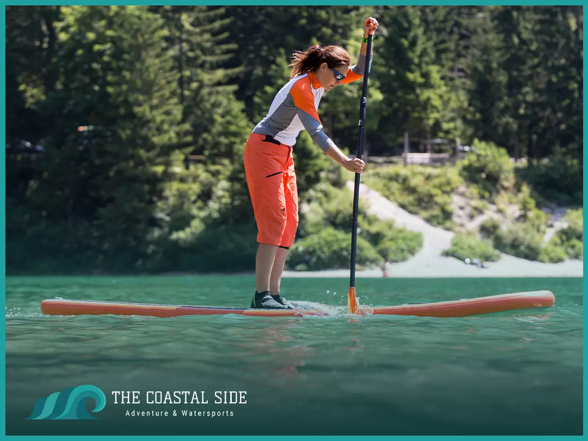 A woman paddle boarding while wearing water shoes