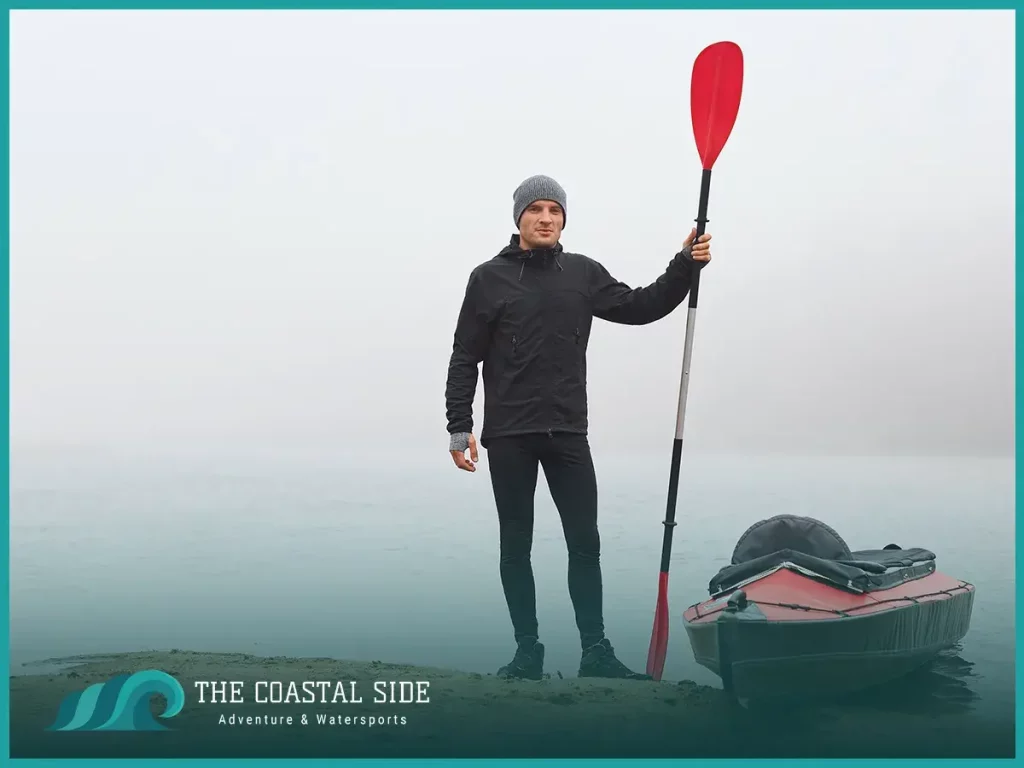Man holding a red kayak paddle in the cold air