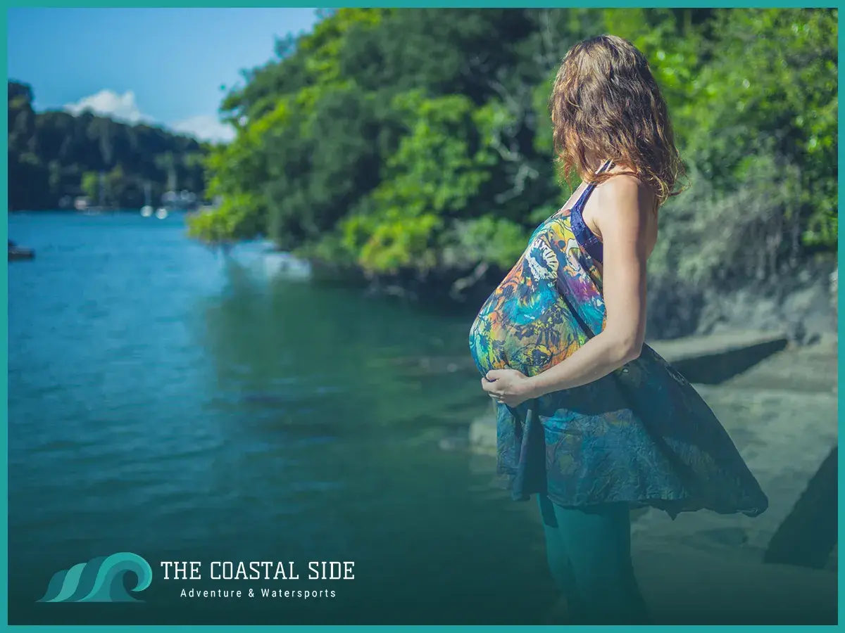 A pregnant woman getting ready to kayak on a lake