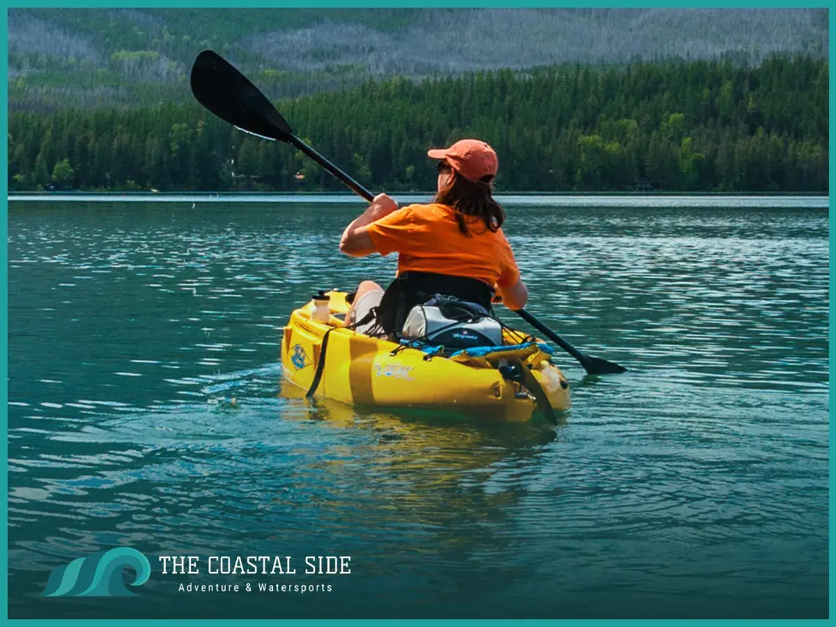 Woman paddling in a yellow kayak wearing an orange shirt