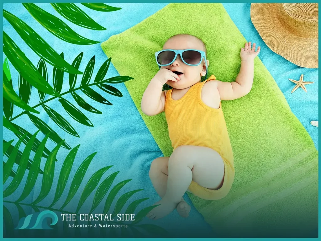 Baby girl in a yellow swimsuit on a green towel at the beach