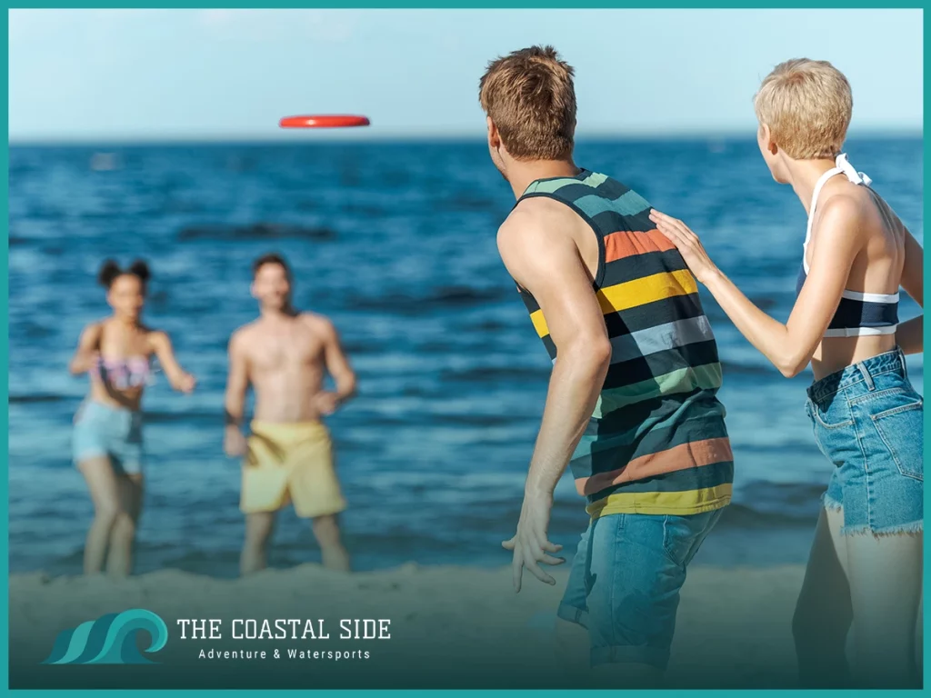 Adults playing frisbee on the beach