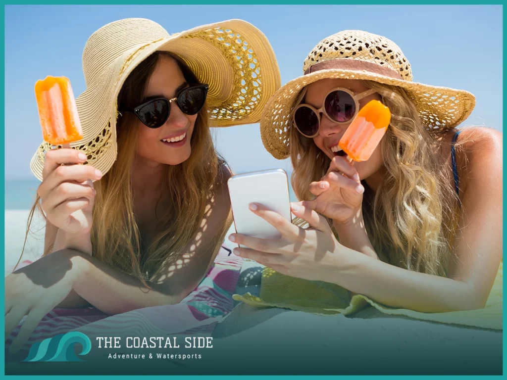 Women wearing floppy straw hats eating ice pops at the beach