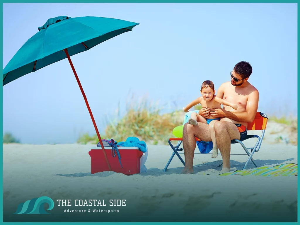 Dad and son sitting under an umbrella at the beach