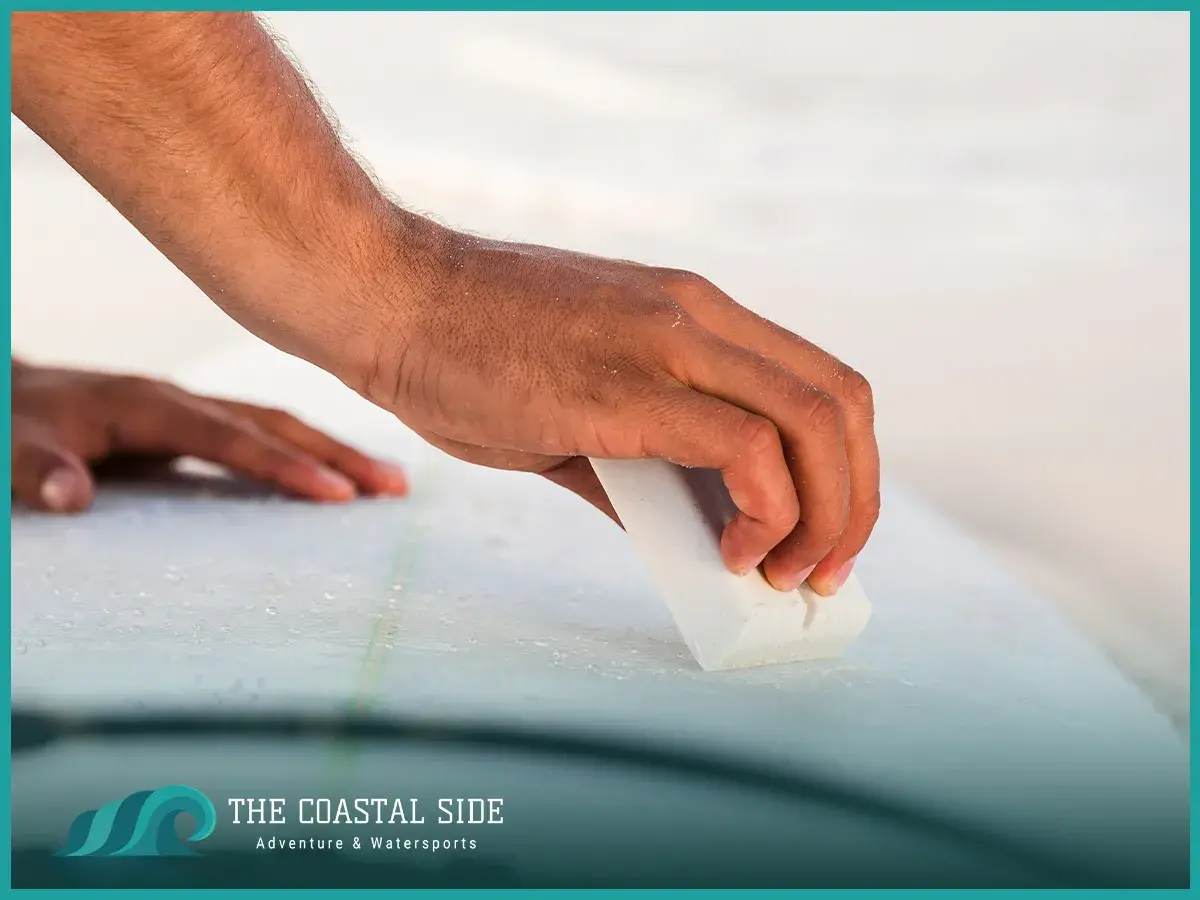 Surfer using surf wax on his surfboard