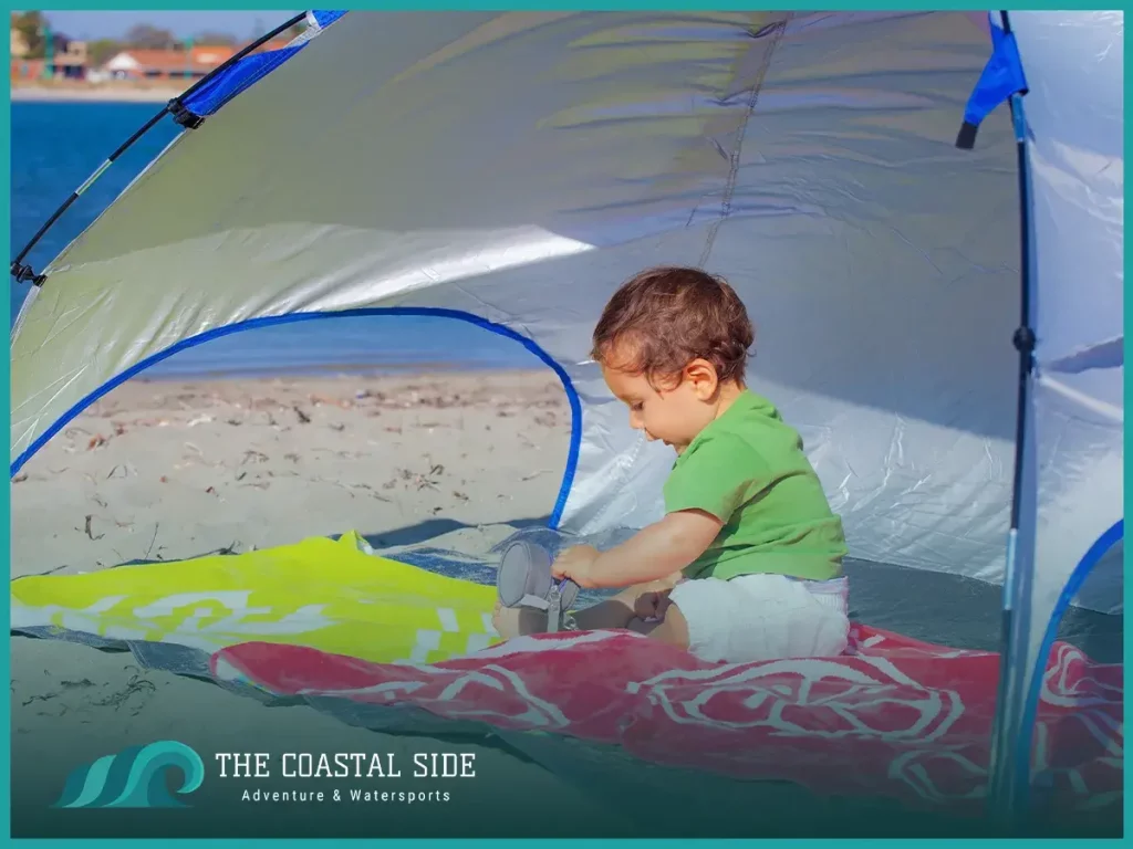 Baby at the beach playing under a pop up tent
