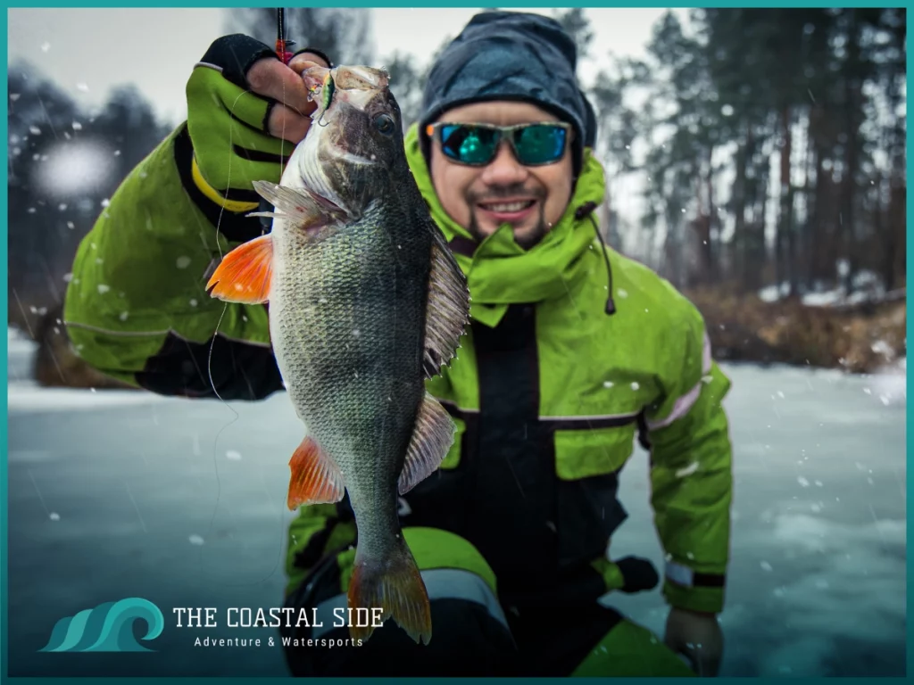 Man in green jacket holding up his ice fishing catch